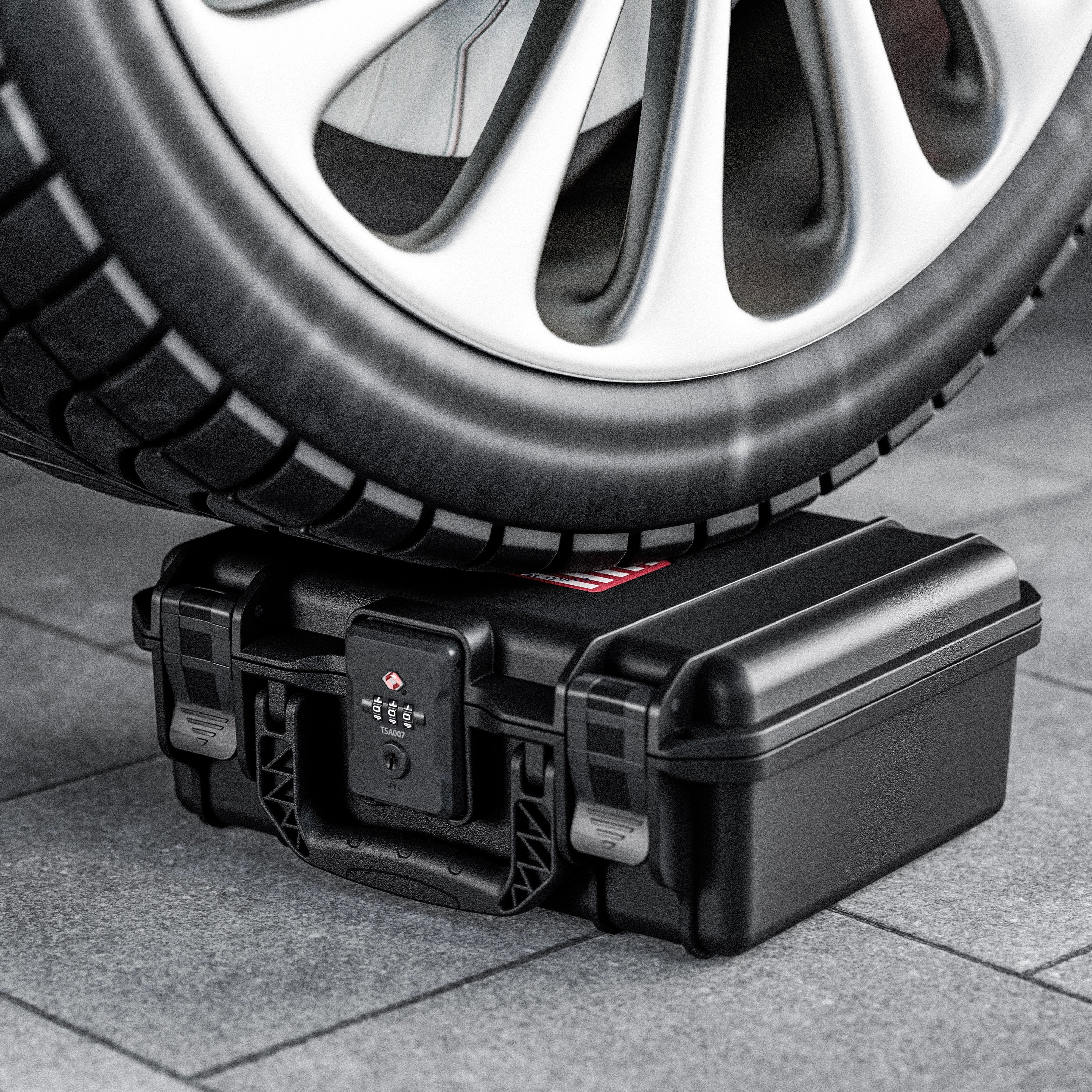 Extreme crushproof and anti-collision test showing a car tire driving over the rugged 11-inch Glock waterproof weapon case.